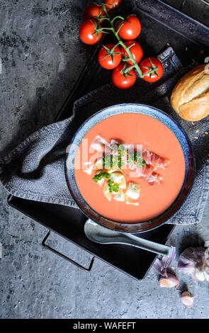 Salmorejo, kalte Tomatensuppe mit Serrano Schinken und Eier in eine keramische Schüssel, serviert mit Gebäck Stockfoto