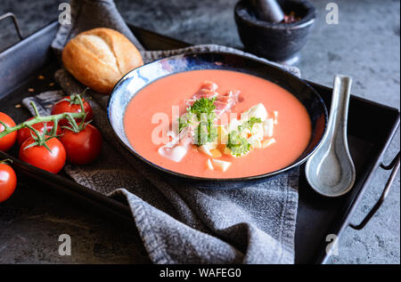 Salmorejo, kalte Tomatensuppe mit Serrano Schinken und Eier in eine keramische Schüssel, serviert mit Gebäck Stockfoto