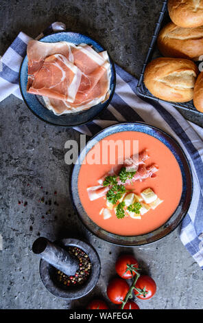 Salmorejo, kalte Tomatensuppe mit Serrano Schinken und Eier in eine keramische Schüssel, serviert mit Gebäck Stockfoto