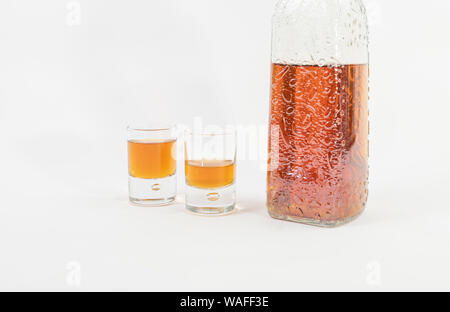 Nahaufnahme von einem rustikalen Flasche Whiskey neben zwei kleinen Gläsern voller Whisky - Lecker und luxuriösen Whisky Stockfoto