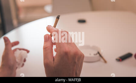 Medizinisches Marihuana joint in der Hand, close-up. Das Rauchen von Cannabis stumpf im Innenbereich. Hanf ist ein Konzept von Kräutermedizin Stockfoto