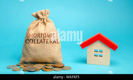Geld beutel mit dem Wort hypothekarischen Sicherheiten und Holzhaus. Erschwinglicher Wohnraum für junge Familien. Staatliche Unterstützung. Kredite und Darlehen. Stockfoto