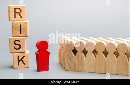 Holzblöcke mit dem Wort Risiko und eine Mannschaft mit einem Führer. Das Konzept der Teamarbeit, Krise, Lösung und Problem Management. Unternehmensplanung. Ri Stockfoto