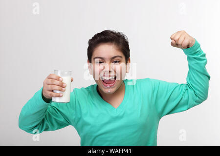 Junge trinkt ein Glas Milch und seine flexing Muskeln angezeigt Stockfoto