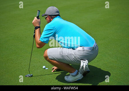 Flache Freiheitsgrad Bild eines jungen Mannes, der Golf hockte sich über das Grün, bevor er seinen Schlag Stockfoto