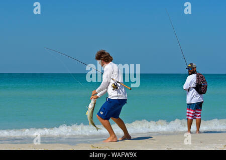 HOLMES BEACH, ANNA MARIA ISLAND, FL - Mai 1, 2018: Zwei junge Männer am Strand angeln im seichten Wasser des Golfs von Mexiko. Stockfoto