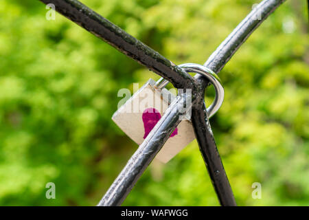 Das Schloss, ein Symbol der Liebe und der Treue, hängt an den Gittern. Rotes Herz malte auf das Schloss. Ein Stück Eisen Baum mit Liebe Schlösser im Park. Die CONCE Stockfoto