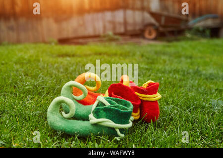 Schuhe Fabelwesen Stehend auf dem Gras, auf dem Hintergrund einer Holzhütte und einem kleinen dreirädrigen Warenkorb Stockfoto