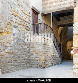 Äußere Tageslicht geschossen von alten, verlassenen Wendeltreppe mit hölzernen Balustrade und Holztür am Stein Ziegel Passage umliegenden Sultan Qalawun Komplex in Al Moez Street, Kairo, Ägypten Stockfoto