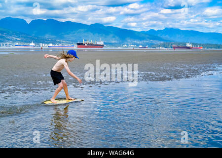 Die jungen langhaarigen Jungen skimboarding, Spanische Banken, English Bay, Vancouver, British Columbia, Kanada Stockfoto