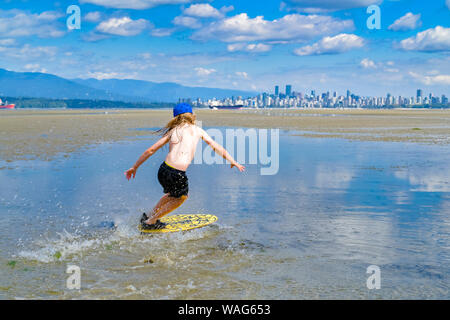 Die jungen langhaarigen Jungen skimboarding, Spanische Banken, English Bay, Vancouver, British Columbia, Kanada Stockfoto