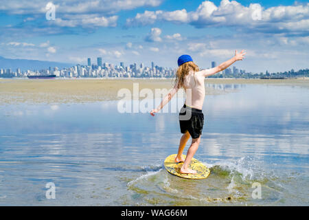 Die jungen langhaarigen Jungen skimboarding, Spanische Banken, English Bay, Vancouver, British Columbia, Kanada Stockfoto