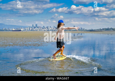 Die jungen langhaarigen Jungen skimboarding, Spanische Banken, English Bay, Vancouver, British Columbia, Kanada Stockfoto