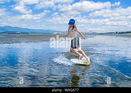 Die jungen langhaarigen Jungen skimboarding, Spanische Banken, English Bay, Vancouver, British Columbia, Kanada Stockfoto