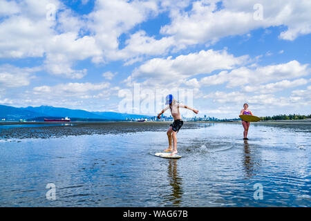 Die jungen langhaarigen Jungen skimboarding, Spanische Banken, English Bay, Vancouver, British Columbia, Kanada Stockfoto