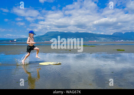 Die jungen langhaarigen Jungen skimboarding, Spanische Banken, English Bay, Vancouver, British Columbia, Kanada Stockfoto