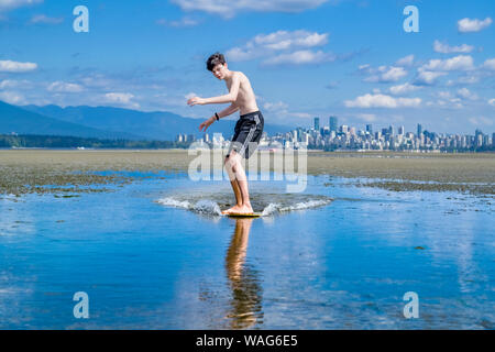 Teenager skimboarding, Spanische Banken, English Bay, Vancouver, British Columbia, Kanada Stockfoto