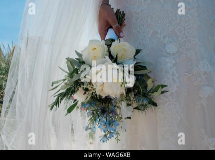 Braut in ihrem Brautkleid aus Spitze mit ihren Blumen bouque Stockfoto