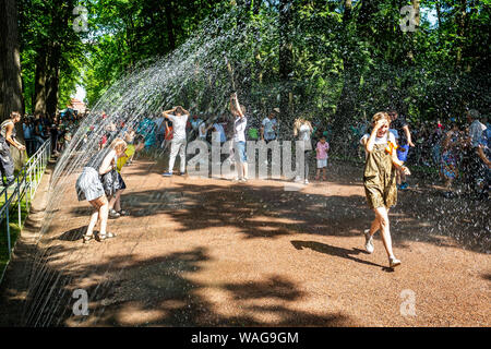 Der Brunnen cracker Wasser weg, auf dem Gelände von Schloss Peterhof, St.-Petersburg, Russland am 22. Juli 2019 - Touristen beobachten Erwachsene und Kinder runni Stockfoto