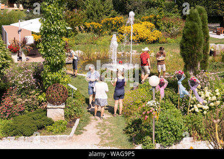 Besucher Kittenberger Erlebnisgärten, einem beliebten botanischen Garten in Niederösterreich, genießen die Pflanzen, Skulpturen und Brunnen an einem Sommertag Stockfoto