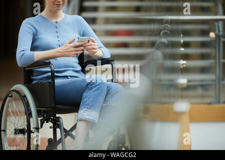 In der Nähe von jungen behinderten Frau sitzt im Rollstuhl und Lesen einer Nachricht auf dem Mobiltelefon Stockfoto