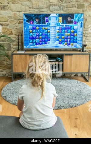 5 fünf Jahre altes Mädchen spielen ein Spiel auf einem großen Bildschirm. Stockfoto