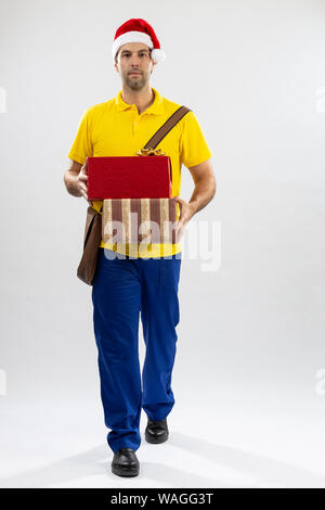 Brasilianische mailman verkleidet als Weihnachtsmann ein Geschenk auf weißem Hintergrund. kopieren. Stockfoto