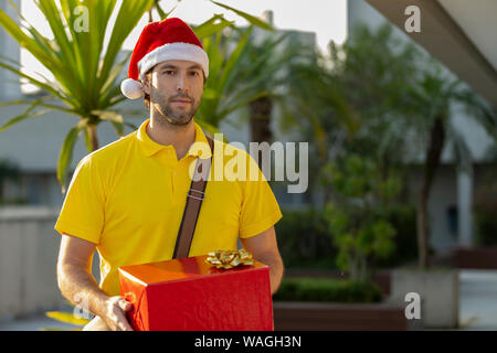 Brasilianische mailman verkleidet als Weihnachtsmann ein Geschenk. Online kaufen In der Auslieferung. Stockfoto