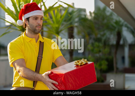 Brasilianische mailman verkleidet als Weihnachtsmann ein Geschenk. Online kaufen In der Auslieferung. Stockfoto