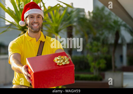 Brasilianische mailman verkleidet als Weihnachtsmann ein Geschenk. Online kaufen In der Auslieferung. Stockfoto