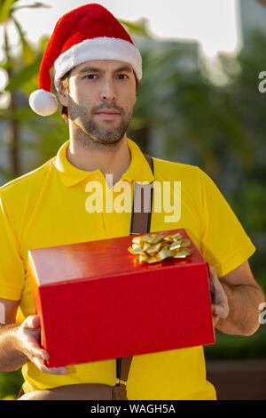 Brasilianische mailman verkleidet als Weihnachtsmann ein Geschenk. Online kaufen In der Auslieferung. Stockfoto