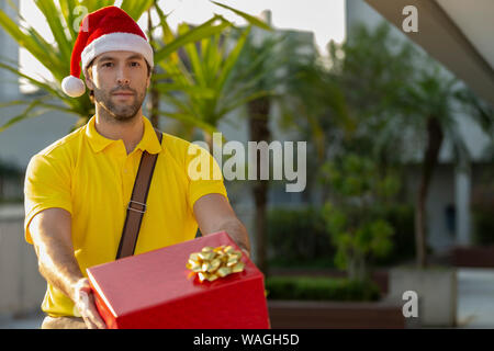 Brasilianische mailman verkleidet als Weihnachtsmann ein Geschenk. Online kaufen In der Auslieferung. Stockfoto