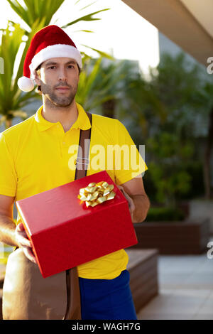 Brasilianische mailman verkleidet als Weihnachtsmann ein Geschenk. Online kaufen In der Auslieferung. Stockfoto