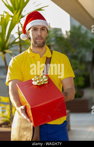 Brasilianische mailman verkleidet als Weihnachtsmann ein Geschenk. Online kaufen In der Auslieferung. Stockfoto