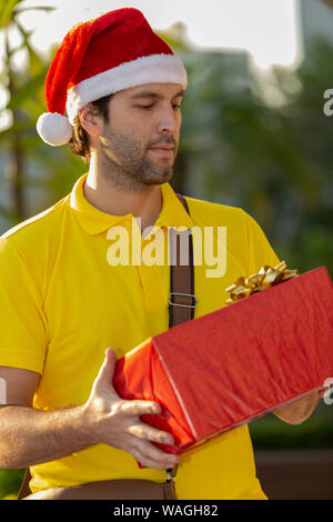 Brasilianische mailman verkleidet als Weihnachtsmann ein Geschenk. Online kaufen In der Auslieferung. Stockfoto