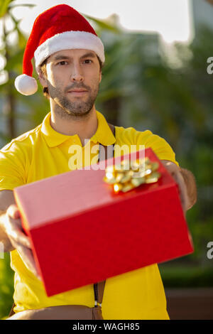 Brasilianische mailman verkleidet als Weihnachtsmann ein Geschenk. Online kaufen In der Auslieferung. Stockfoto