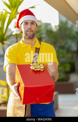 Brasilianische mailman verkleidet als Weihnachtsmann ein Geschenk. Online kaufen In der Auslieferung. Stockfoto