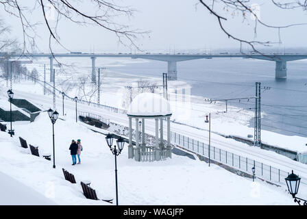 Perm, Russland - März 06, 2019: Winter verschneite Gasse mit Vintage Laternen und Pavillon in der Nähe des Bahnhofes am Ufer, ein paar Leute, die in der Stockfoto