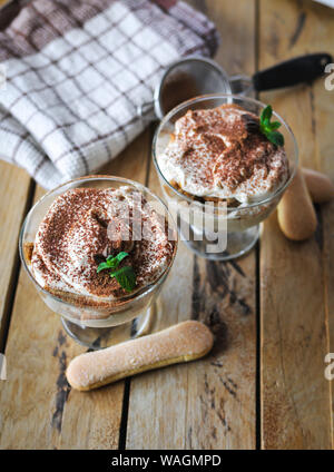 Classic tiramisu Kuchen in ein Glas mit frischer Minze, auf hölzernen Hintergrund Stockfoto