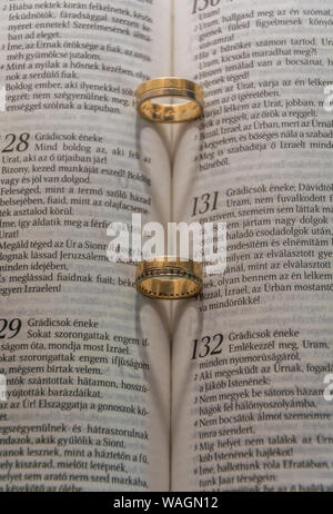 Ringe bilden ein Herz der Schatten auf eine Bibel. Dieses Bild stellt Einheit, Liebe und Nähe zwischen ein paar. Der Ring des Schatten erzeugen ein Herz auf ein Buch. Stockfoto