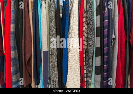 Zeile aus Gewirken und Gestricken Pullover Pullover hängen auf Aluminium Kleiderbügel Kleiderständer im Einzelhandel Fashion Store oder second hand outlet shop. Stockfoto