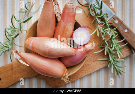 Close-up von schalotten mit frischem Rosmarin auf Schneidebrett, Ansicht von oben Stockfoto