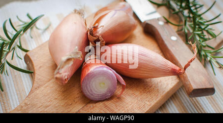 Close-up von schalotten mit frischem Rosmarin auf Schneidebrett Stockfoto