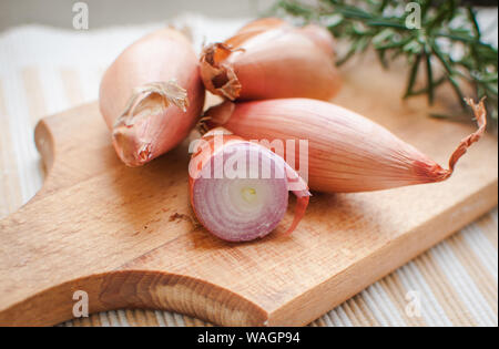 Close-up von schalotten mit frischem Rosmarin auf Schneidebrett Stockfoto