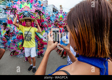 Eine junge Frau macht ein Foto von einer bunten Prozession während der ati-atihan-Festival, Kalibo, Panay Island, Aklan Provinz, die Philippinen Stockfoto