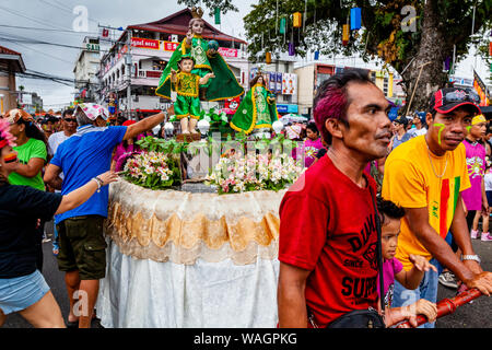 Eine Prozession der Schwimmer mit Santo Nino Statuen Teil in einer Straße Prozession während der ati-atihan-Festival, Kalibo, Panay Island, Philippinen. Stockfoto