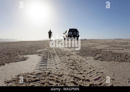 Mann zu Fuß von seinem 4x4 Auto auf den Spuren von Reifen in der Nähe von Al Khaluf Dorf, Oman Stockfoto