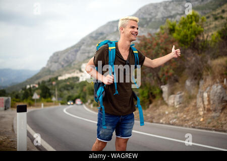 Reisen Mann backpacking per Anhalter auf Straße Reise hitching eine Fahrt aus dem Auto Stockfoto