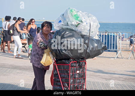 Eine Frau mittleren Alters sammeln Kaution Flaschen auf dem Boardwalk in Coney Island, Brooklyn, New York City. Stockfoto