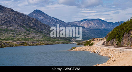 Schmalspurbahn Titel in der Nähe von White Pass an einem See südlich von Fraser British Columbia mit Berge und Wolken im Hintergrund ausgeführt werden Stockfoto